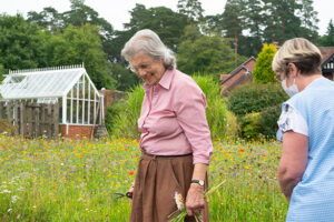 Resident With Carer Picking Flowers