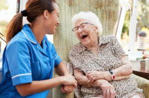 Elderly lady laughing with young carer in residential care setting