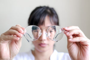 Woman holding glasses infront of her face - eye health